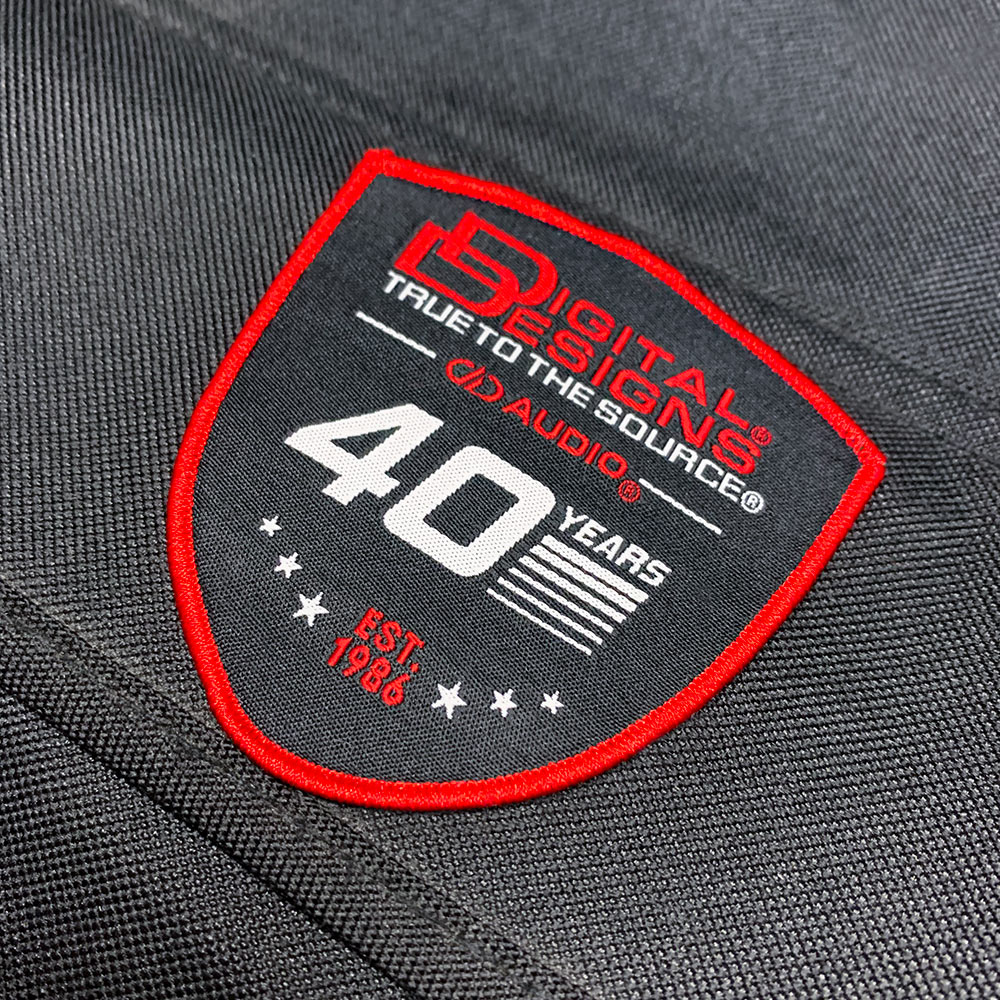 DD 40th Anniversary Woven Patches - photo of Digital Designs patch adhered to twill black fabric - Patch contains classic Digital Designs style logo, True to the Source slogan, modern DD AUDIO logo, 40 Years design and EST 1986 with starts and bars